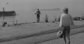 Movie still from “Broadway Danny Rose” (1984), directed by Woody Allen – A man and a woman standing on the side of a road; Wide shot, Over the shoulder angle