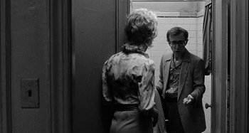 Movie still from “Broadway Danny Rose” (1984), directed by Woody Allen – A man and a woman standing next to each other in a doorway; Medium shot, Over the shoulder angle
