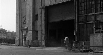 Movie still from “Broadway Danny Rose” (1984), directed by Woody Allen – A man walking down the street in front of an old building; Extreme Wide shot, Low angle