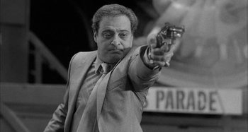 Movie still from “Broadway Danny Rose” (1984), directed by Woody Allen – A black and white photo of a man holding a gun; Medium shot, Low angle