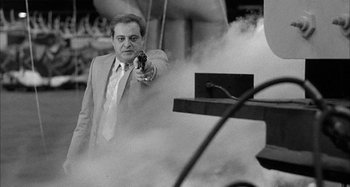 Movie still from “Broadway Danny Rose” (1984), directed by Woody Allen – A black and white photo of a man holding a gun; Medium shot, Low angle