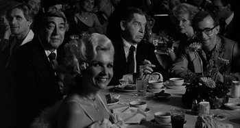 Movie still from “Broadway Danny Rose” (1984), directed by Woody Allen – A group of people sitting at a table with plates of food; Medium shot, Over the shoulder angle