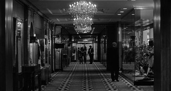 Movie still from “Broadway Danny Rose” (1984), directed by Woody Allen – Three people are standing in a hallway of a hotel; Wide shot, High angle