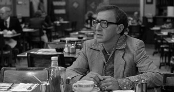 Movie still from “Broadway Danny Rose” (1984), directed by Woody Allen – A man sitting at a table in front of a cake; Medium shot, Over the shoulder angle