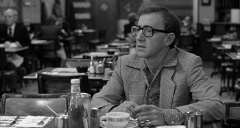 Movie still from “Broadway Danny Rose” (1984), directed by Woody Allen – A man sitting at a table in front of a cake; Medium shot, Over the shoulder angle