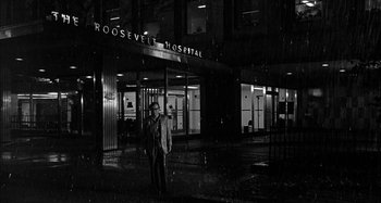Movie still from “Broadway Danny Rose” (1984), directed by Woody Allen – A man standing in front of a hospital at night; Extreme Wide shot, Low angle