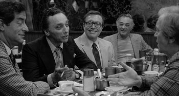 Movie still from “Broadway Danny Rose” (1984), directed by Woody Allen – A group of men sitting at a table with food; Medium shot, Over the shoulder angle