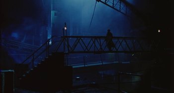 A man walking across a bridge in the dark