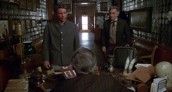 Movie still from “Butch and Sundance: The Early Days” (1979), directed by Richard Lester – Two men are standing at a table in front of a woman; Medium shot, Over the shoulder angle