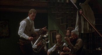 Movie still from “Butch and Sundance: The Early Days” (1979), directed by Richard Lester – A group of people playing musical instruments in a room; Wide shot, Low angle