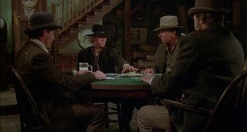 Movie still from “Butch and Sundance: The Early Days” (1979), directed by Richard Lester – A group of men sitting at a table playing cards; Medium shot, High angle
