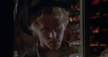 Movie still from “Butch and Sundance: The Early Days” (1979), directed by Richard Lester – A man with blonde curly hair wearing a hat looking out of a window; Close Up shot, Low angle