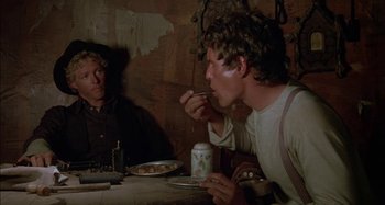 Movie still from “Butch and Sundance: The Early Days” (1979), directed by Richard Lester – Two men sitting at a dinner table eating food; Medium shot, Over the shoulder angle