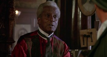 Movie still from “Butch and Sundance: The Early Days” (1979), directed by Richard Lester – An older black man wearing a red and black vest; Close Up shot, Over the shoulder angle