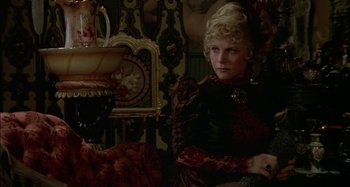 Movie still from “Butch and Sundance: The Early Days” (1979), directed by Richard Lester – A woman sitting in a chair in a room with ornate furniture; Medium shot, Over the shoulder angle