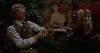 Movie still from “Butch and Sundance: The Early Days” (1979), directed by Richard Lester – A man sitting at a table holding a nintendo wii game controller; Medium shot, Over the shoulder angle