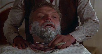 Movie still from “Butch and Sundance: The Early Days” (1979), directed by Richard Lester – A man with a beard is being shaved by another man; Close Up shot, Low angle