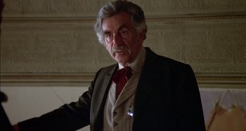 Movie still from “Butch and Sundance: The Early Days” (1979), directed by Richard Lester – An older man in a suit and a red neck tie; Close Up shot, Low angle