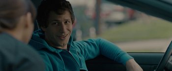 Movie still from “Celeste & Jesse Forever” (2012), directed by Lee Toland Krieger – A young man sitting in a chair smiling for the camera; Close Up shot, Over the shoulder angle