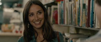 Movie still from “Celeste & Jesse Forever” (2012), directed by Lee Toland Krieger – A woman smiling for the camera in front of a book shelf; Close Up shot, Over the shoulder angle