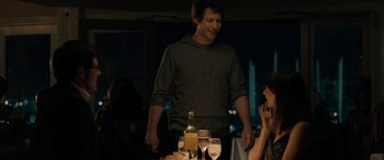 Movie still from “Celeste & Jesse Forever” (2012), directed by Lee Toland Krieger – A man standing next to a woman at a dinner table; Medium shot, Over the shoulder angle
