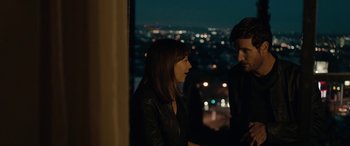 Movie still from “Celeste & Jesse Forever” (2012), directed by Lee Toland Krieger – A woman and a man standing next to each other in front of a window at night; Medium shot, Over the shoulder angle