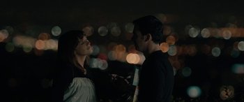 Movie still from “Celeste & Jesse Forever” (2012), directed by Lee Toland Krieger – A man and a woman standing next to each other in front of lights; Medium shot, Over the shoulder angle