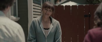 Movie still from “Celeste & Jesse Forever” (2012), directed by Lee Toland Krieger – A woman in a gray jacket standing in front of a fence; Medium shot, Over the shoulder angle