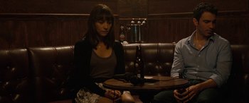 Movie still from “Celeste & Jesse Forever” (2012), directed by Lee Toland Krieger – A woman sitting at a table with a bottle of beer; Medium shot, Over the shoulder angle