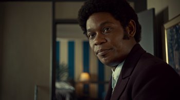Movie still from “Fargo” (2014), created by Noah Hawley – A man in a suit is smiling for the camera; Close Up shot, Over the shoulder angle