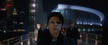 Movie still from “Code 46” (2003), directed by Michael Winterbottom – A woman in a black jacket and a black hat is in a crowd; Close Up shot, Low angle