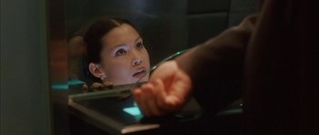 Movie still from “Code 46” (2003), directed by Michael Winterbottom – A woman looking into a mirror while holding her hand out; Close Up shot, Over the shoulder angle