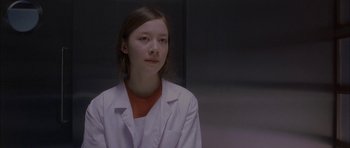 Movie still from “Code 46” (2003), directed by Michael Winterbottom – A woman in a white lab coat looking at the camera; Close Up shot, Low angle