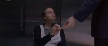 Movie still from “Code 46” (2003), directed by Michael Winterbottom – A woman is looking up at a person holding a pen; Medium shot, High angle