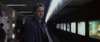 Movie still from “Code 46” (2003), directed by Michael Winterbottom – A man standing in front of a train platform; Close Up shot, Low angle