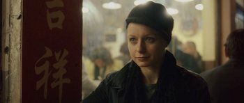 Movie still from “Code 46” (2003), directed by Michael Winterbottom – A woman in a black jacket and a black hat; Close Up shot, Over the shoulder angle