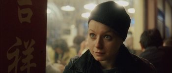 Movie still from “Code 46” (2003), directed by Michael Winterbottom – A woman in a black jacket and a black hat; Close Up shot, High angle