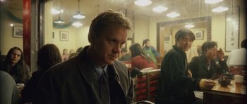 Movie still from “Code 46” (2003), directed by Michael Winterbottom – A man in a suit and tie sitting in a restaurant; Close Up shot, Over the shoulder angle