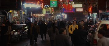 Movie still from “Code 46” (2003), directed by Michael Winterbottom – A crowd of people walking down a street at night; Extreme Wide shot, High angle
