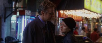 Movie still from “Code 46” (2003), directed by Michael Winterbottom – A man and a woman standing next to each other in front of lights; Close Up shot, Low angle