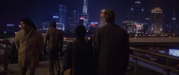 Movie still from “Code 46” (2003), directed by Michael Winterbottom – A group of people standing next to each other on a bridge; Wide shot, Over the shoulder angle