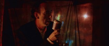 Movie still from “Code 46” (2003), directed by Michael Winterbottom – A man holding a microphone up to his mouth; Close Up shot, Low angle