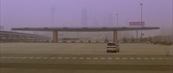 Movie still from “Code 46” (2003), directed by Michael Winterbottom – A car parked on the side of a road near a bridge; Extreme Wide shot, High angle
