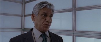 Movie still from “Code 46” (2003), directed by Michael Winterbottom – An older man in a suit and tie looking to his left; Close Up shot, Low angle