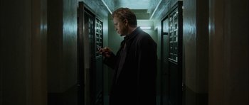 Movie still from “Code 46” (2003), directed by Michael Winterbottom – A man standing in a hallway looking at his cell phone; Medium shot, Low angle