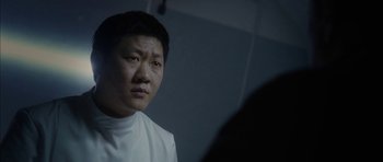 Movie still from “Code 46” (2003), directed by Michael Winterbottom – A man wearing a white shirt looking at the camera; Close Up shot, Over the shoulder angle