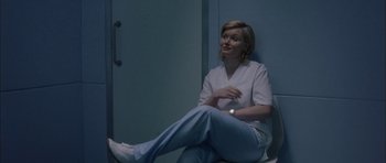 Movie still from “Code 46” (2003), directed by Michael Winterbottom – A woman sitting on a chair in a room; Medium shot, Low angle