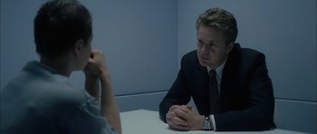 Movie still from “Code 46” (2003), directed by Michael Winterbottom – A man in a suit sitting at a table talking to a woman; Close Up shot, Over the shoulder angle