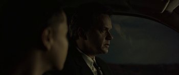 Movie still from “Code 46” (2003), directed by Michael Winterbottom – A man wearing a suit and tie in the dark; Close Up shot, Over the shoulder angle