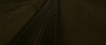 Movie still from “Code 46” (2003), directed by Michael Winterbottom – An aerial view of an empty highway at night; Extreme Wide shot, High angle